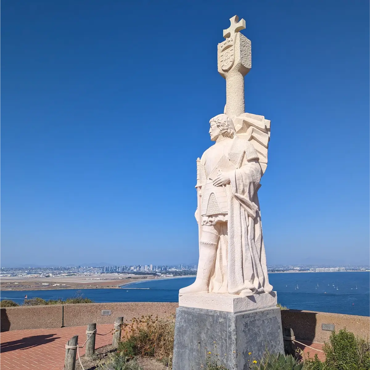 A view of the statue at Cabrillo National Monument in Point Loma with the San Diego city skyline in the background. 