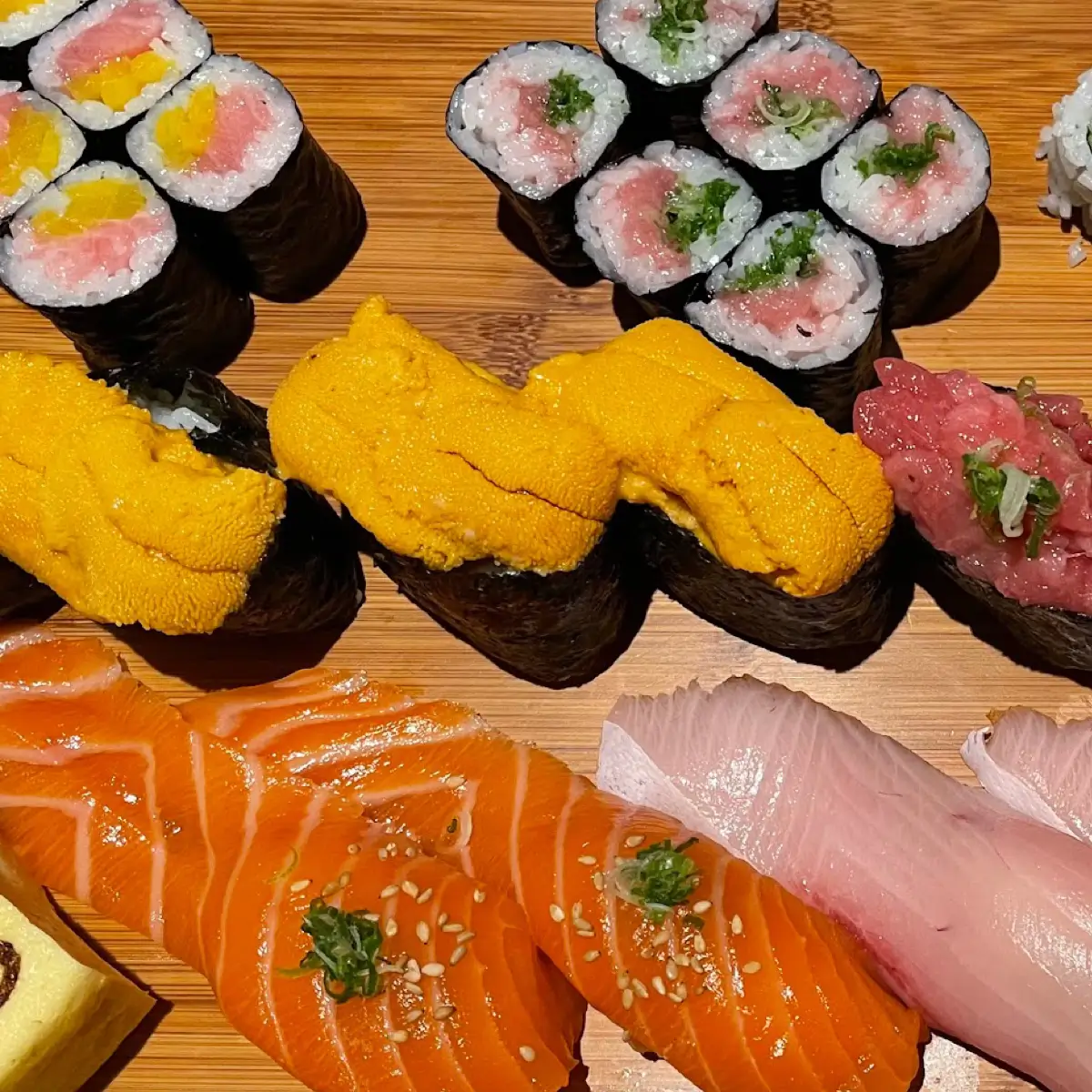 Different types of nigiri sushi including salmon, yellowtail and sushi rolls. 